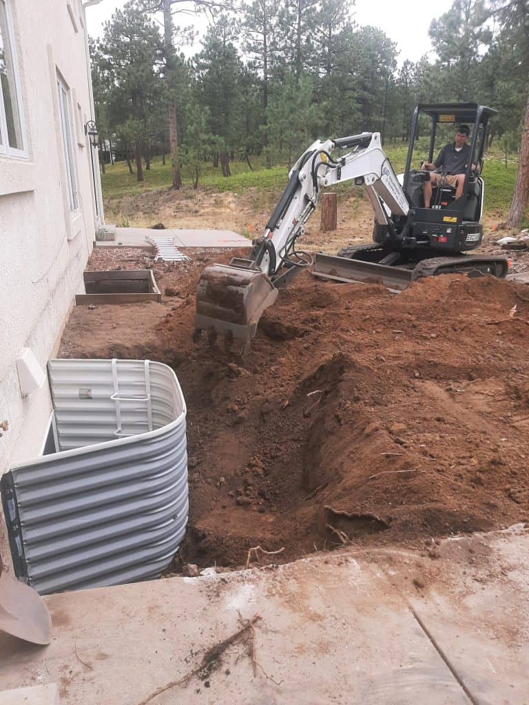 Outdoor Living excavator from another angle digging out window wells