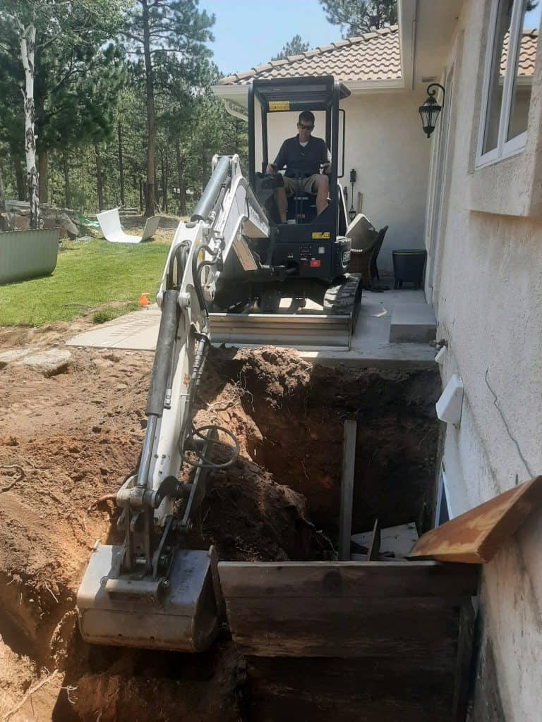 Outdoor living excavator digging out window wells